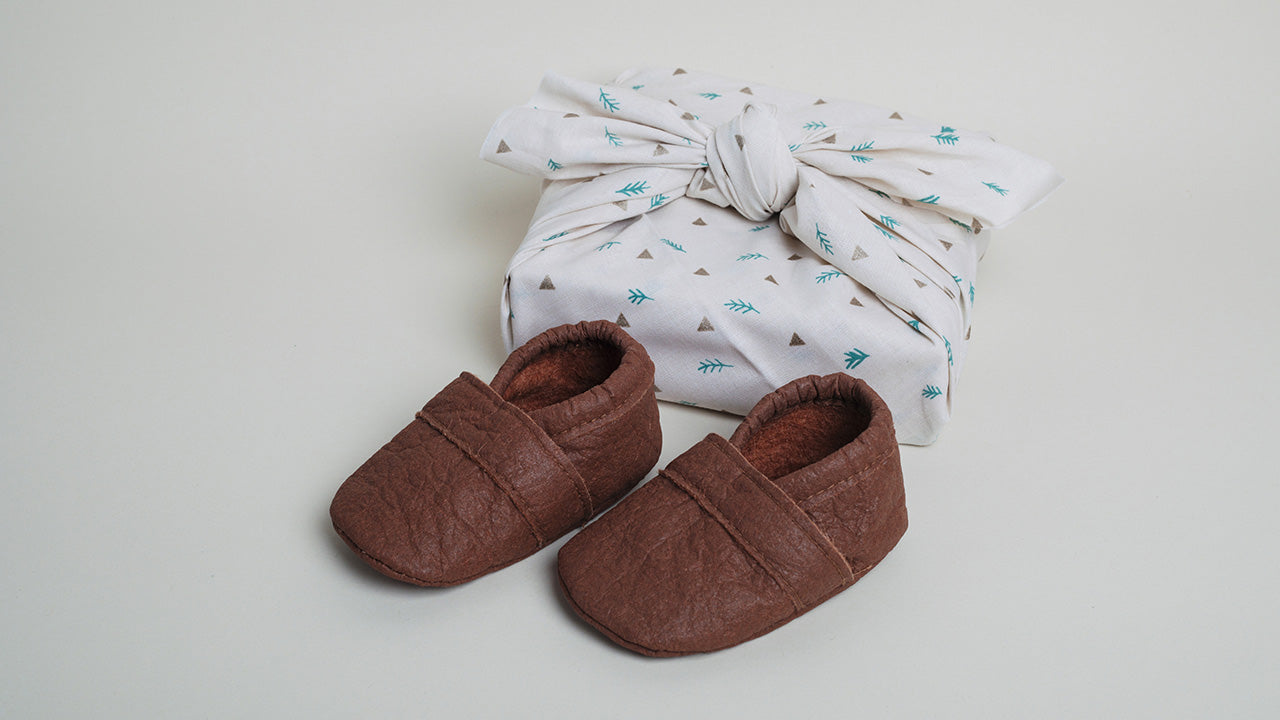 Das perfekte Geschenk: Krabbelschuhe in Zimtbraun aus Piñatex - stilvoll verpackt.